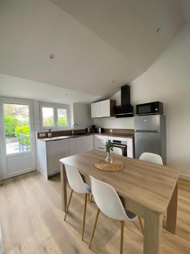 - une cuisine avec une table en bois et des chaises blanches dans l'établissement Les Apparts de St Mart, à Bréhal