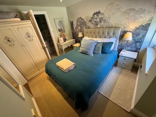 a bedroom with a large bed with blue sheets and pillows at Charming one bedroom cottage in Basingstoke