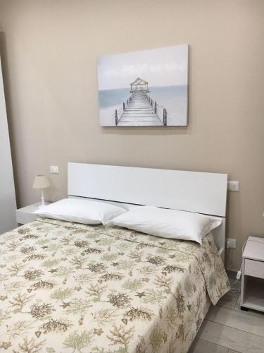 ein Schlafzimmer mit einem Bett mit einem Bild an der Wand in der Unterkunft Casa Vacanze San Giacomo App Perla in Santo Stefano al Mare