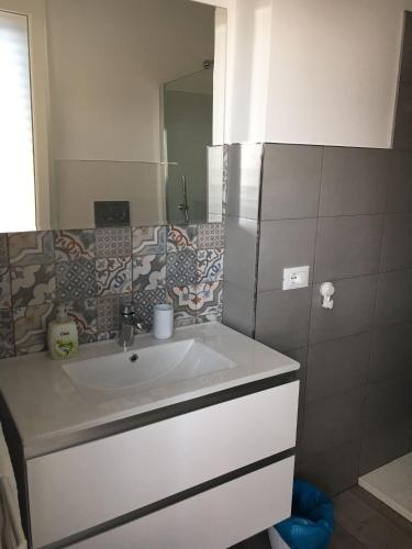 ein Bad mit einem Waschbecken und einem Spiegel in der Unterkunft Casa Vacanze San Giacomo App Perla in Santo Stefano al Mare