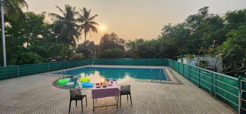 a pool with a table and chairs in front of it at ABHISHEK AGRO FARM in Panvel