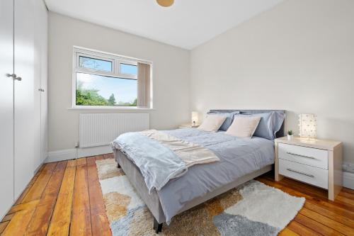 a white bedroom with a bed and a window at Fantastic, modern 3 bedroom house in Manchester