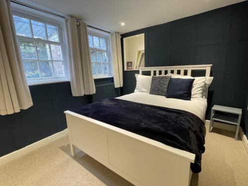 a bedroom with a white bed and two windows at Apartment 1 St Georges in Cheltenham
