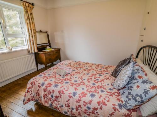 a bedroom with a bed and a dresser and a window at James Neills Cottage in Letterkenny
