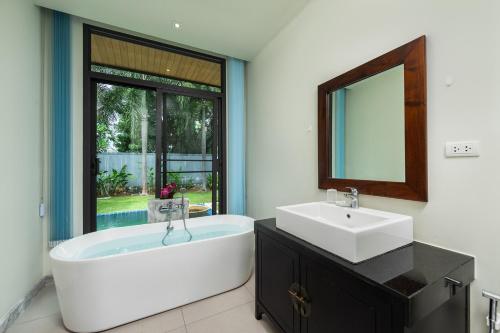 a bathroom with a tub and a sink and a mirror at Beautiful villa with 3BR in Saiyuan Estate with Yoga house in Ban Saiyuan (1)