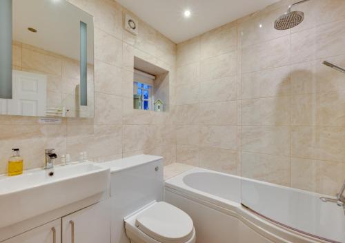 een badkamer met een wastafel, een toilet en een bad bij Cutter Cottage in Swanage