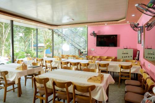 a restaurant with tables and chairs in a room with pink walls at Tran Chau Garden Home in Cat Ba