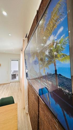 a large screen tv with a palm tree on a wall at AMAO Obsidian - 120 m2 Business & Family Apartment - 3 Bedrooms - 8 Guests - King-Size Beds in Schwanau