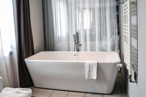 La salle de bains est pourvue d'une baignoire blanche et d'une fenêtre. dans l'établissement Hotel K'Loys, à Paimpol