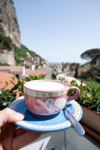 a person holding a cup on a plate on a balcony at Valle d'Amalfi Suites in Amalfi