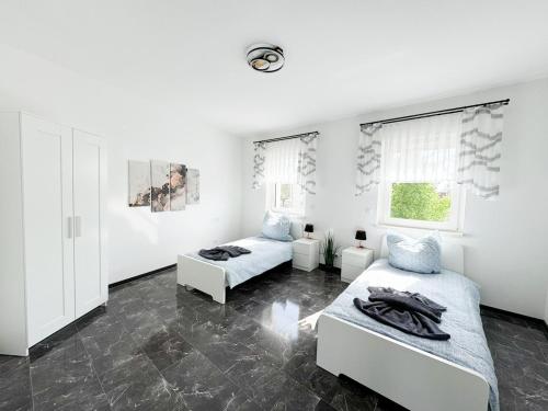 a white room with two beds and two windows at Ferienwohnung Zum Alten Radlereck in Lauchhammer