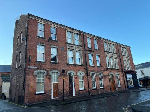 a red brick building on a street with a street at Thurnams House, Ground Floor Apt in Carlisle