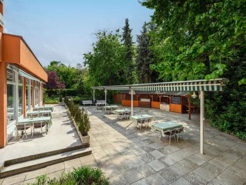 eine Terrasse mit Tischen und Stühlen neben einem Gebäude in der Unterkunft Ibis Budapest Citysouth in Budapest