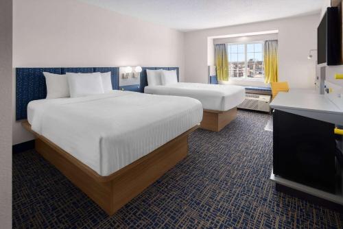 ein Hotelzimmer mit 2 Betten und einem TV in der Unterkunft Microtel Inn and Suites Dover in Dover