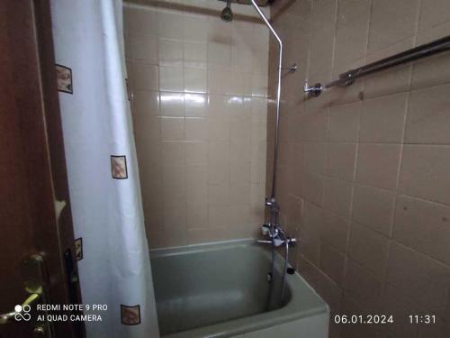 ein Bad mit einer Badewanne und einer Dusche mit einem Duschvorhang in der Unterkunft Хотел Казанлък in Kasanlak