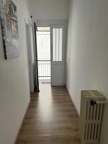 an empty room with a hallway with a door and wooden floors at Appartamenti Monti Como Lake in Brunate