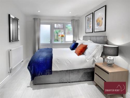 a bedroom with a bed with a blue blanket and a window at Bracknell -58c Harmanswater Road - 2 bedroom apartment in Bracknell