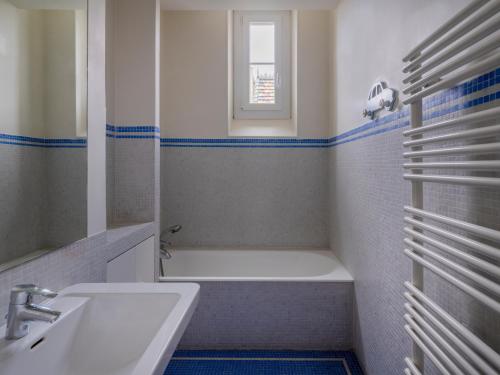 Paris Mozart Prestige Residence في باريس: حمام مع حوض أبيض ومغسلة
