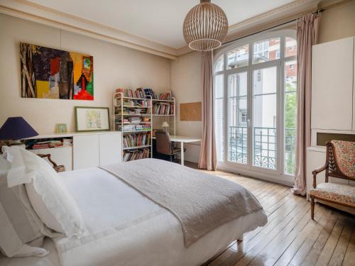Paris Mozart Prestige Residence في باريس: غرفة نوم بسرير ومكتب ونافذة