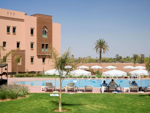 un complexe avec une piscine et un bâtiment dans l'établissement Ibis Marrakech Palmeraie, à Marrakech
