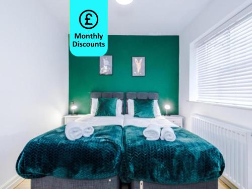 a green bedroom with a bed with towels on it at Lovely 3 Bed house - Park Lane in Manchester