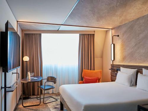 a hotel room with a bed and a table and a chair at Novotel München Airport in Freising