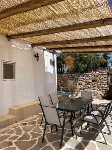 un patio con mesa, sillas y pared de piedra. en Cantera house, Kalokairines KIT en Kýthira