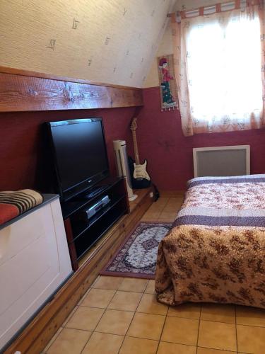 a bedroom with a bed and a flat screen tv at Yufan in La Ville-du-Bois