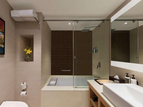 a bathroom with a shower and a sink at Novotel Lucknow Gomti Nagar in Lucknow