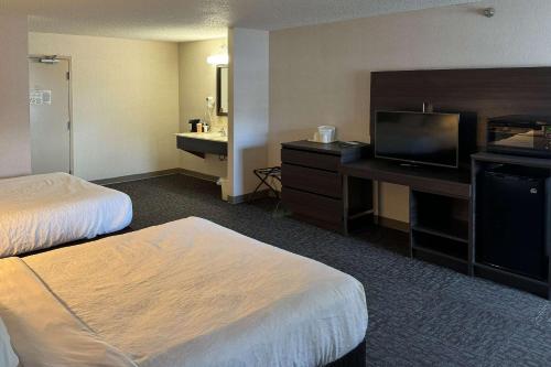 a hotel room with two beds and a flat screen tv at Quality Inn Spearfish in Spearfish