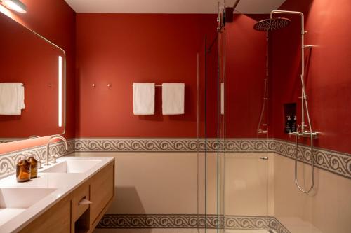 uma casa de banho com paredes vermelhas, um chuveiro e um lavatório. em Cresta Palace Celerina em Celerina