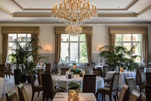 uma sala de jantar com mesas e cadeiras e um lustre em Cresta Palace Celerina em Celerina