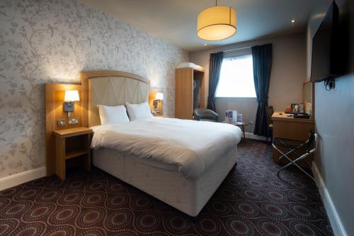 a hotel room with a large bed and a window at Sandford House Hotel Wetherspoon in Huntingdon