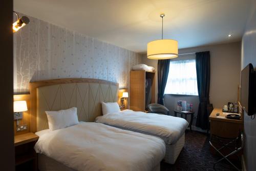 a hotel room with two beds and a window at Sandford House Hotel Wetherspoon in Huntingdon