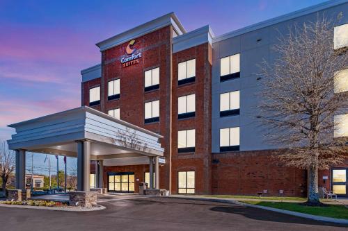 a large brick building with a gas station in front at Comfort Suites Murfreesboro Shopping District in Murfreesboro