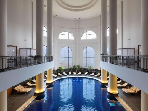 a pool in a large building with columns and windows at Rixos Krasnaya Polyana Sochi in Estosadok