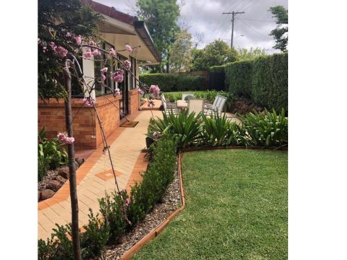 un jardín con un patio con flores rosas en Hedge House - luxury, space, style, great location, en Toowoomba