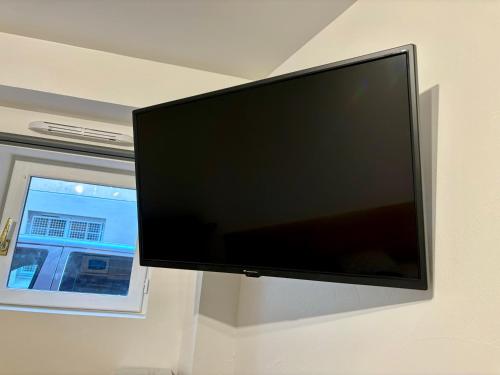 uma televisão de ecrã plano pendurada numa parede ao lado de uma janela em studio - baignoire - prêt de vtt - lave linge em Le Puy-en-Velay
