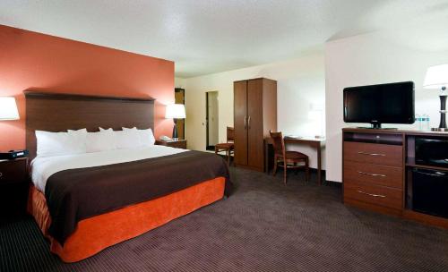 a hotel room with a bed and a flat screen tv at AmericInn by Wyndham Manitowoc in Manitowoc