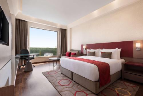 a hotel room with a large bed and a large window at Ramada Plaza by Wyndham Lucknow in Lucknow