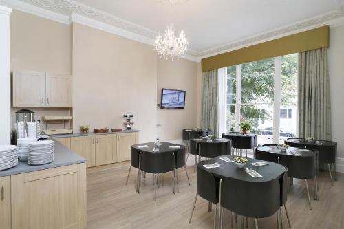 a dining room with black chairs and a kitchen at Hyde Park Boutique Hotel in London