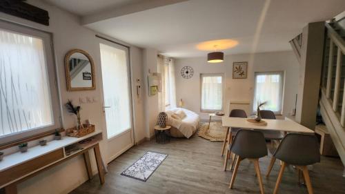 een woonkamer met een tafel en een aantal ramen bij Maison L'Atelier des Salines in Lons-le-Saunier