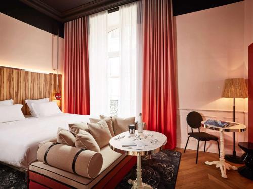um quarto de hotel com uma cama, um sofá e uma mesa em Mama Shelter Rennes em Rennes