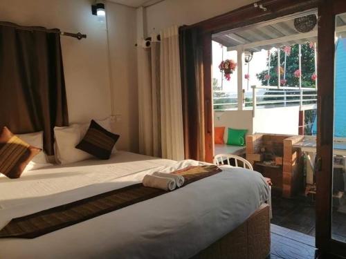 a bedroom with a bed and a large window at Ingmhok Resort in Suan Phung