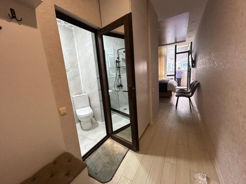 a hallway with a bathroom with a toilet and a mirror at Alley Palace ბათუმი in Angisa
