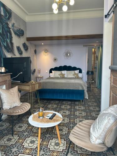 um quarto com uma cama azul e 2 cadeiras em MAISON La BOHEME Spa & Jacuzzi em Vias