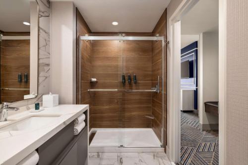 uma casa de banho com um chuveiro e um lavatório. em Hilton BNA Nashville Airport Terminal em Nashville
