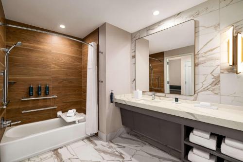 a bathroom with a tub and a sink and a mirror at Hilton BNA Nashville Airport Terminal in Nashville