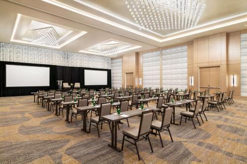 a conference room with tables and chairs and a screen at Hilton BNA Nashville Airport Terminal in Nashville