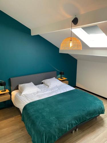 1 dormitorio azul con 1 cama con manta verde en Le Trou du Bois, en Thimister